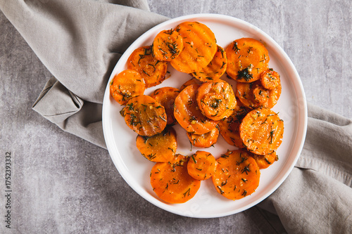Close up of pieces of fried carrots with garlic and herbs on a plate on the table top view