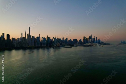 4K cinematic aerial drone video of New York City Manhattan skyscrapers panorama across Hudson river at sunrise on a sunny day with clear skies as seen from New Jersey, United states of America