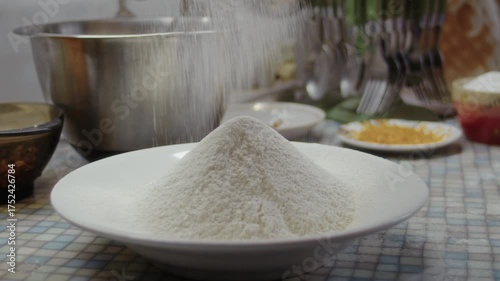 Close-up, sifting flour through a sieve into a plate on the kitchen counter to make a pumpkin cake