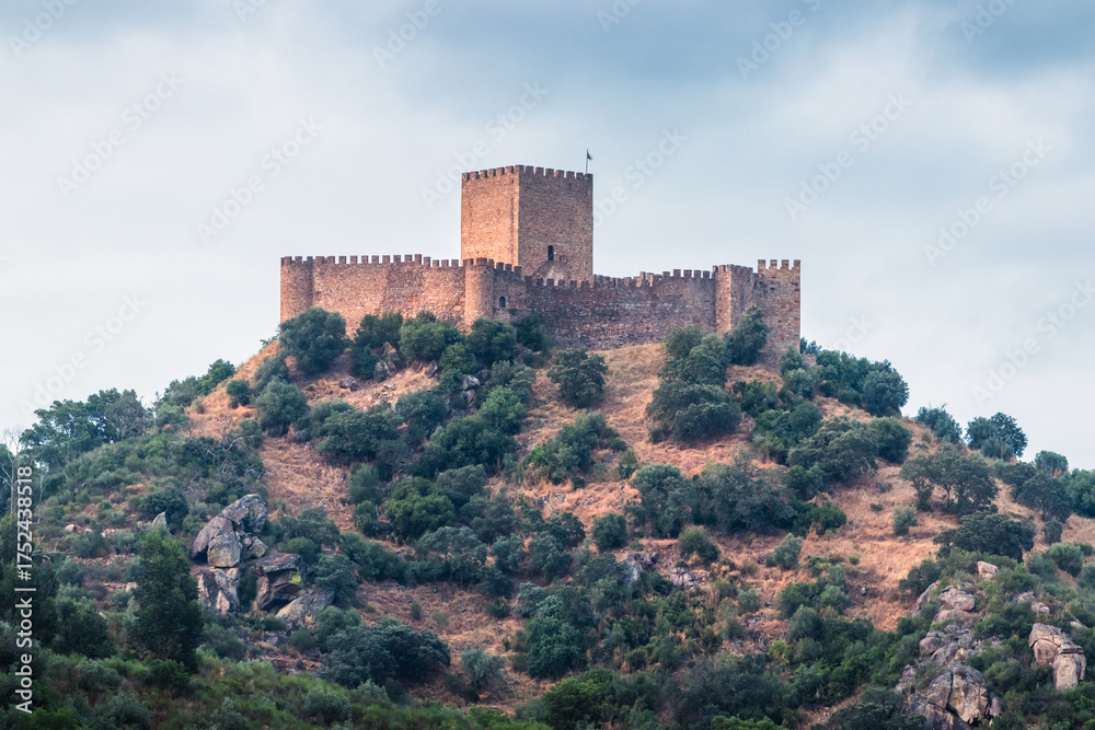Obraz premium Belver Castle on top of a hill at sunset, with a serene sky and soft clouds in Portugal.