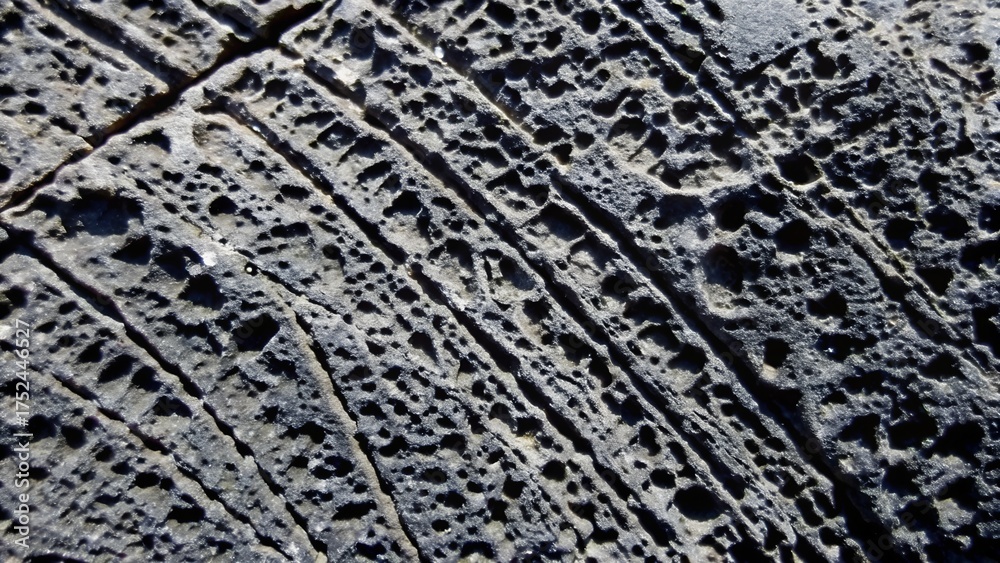 Naklejka premium Weathered dark basalt rock erosion texture surface