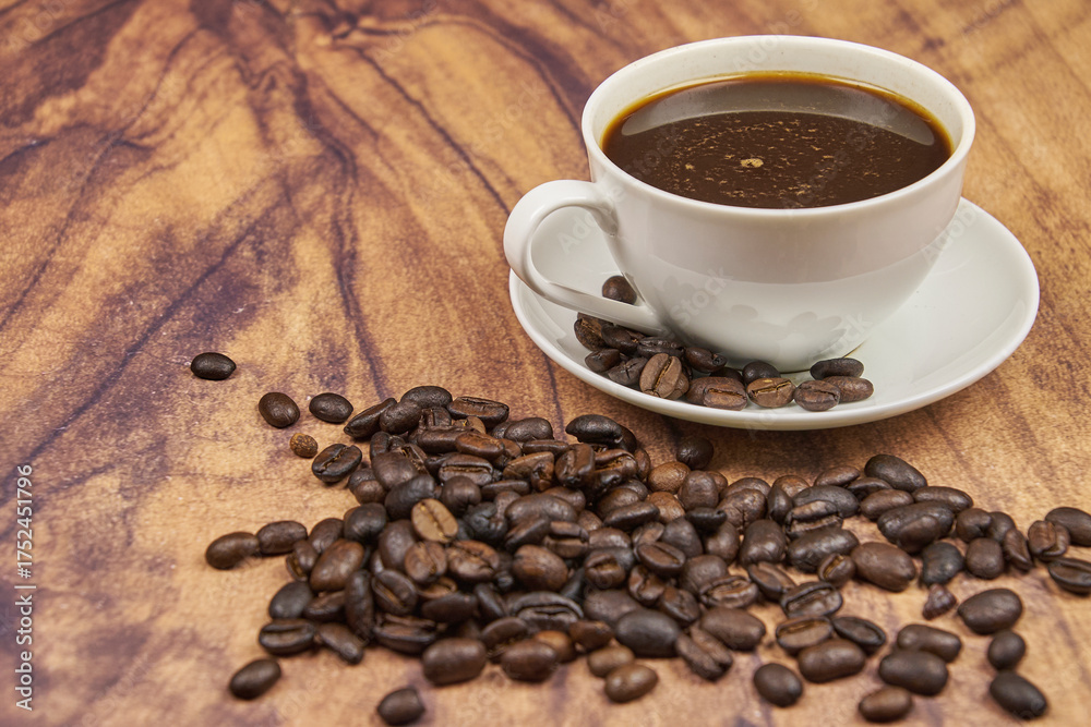 Naklejka premium Coffee cup, foreground, with freshly roasted beans in a jute sack on a rustic wooden table with copy space