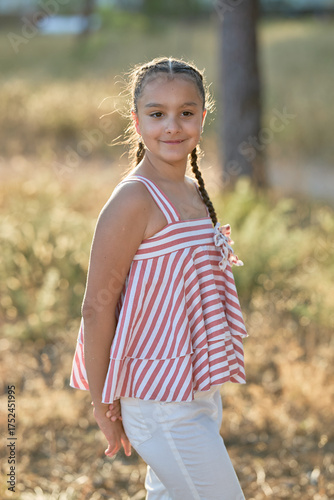 Young girl posing in striped summer top in a sunlit outdoor setting during golden hour