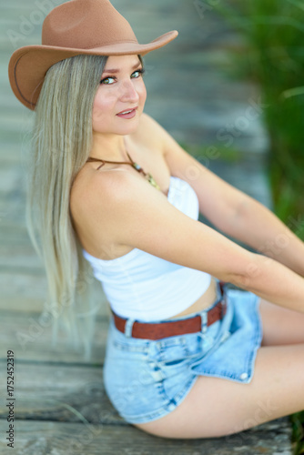 Young cowgirl in stylish western outfit by the river