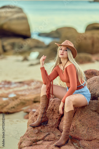 Young cowgirl posing outdoors in western fashion at sunset