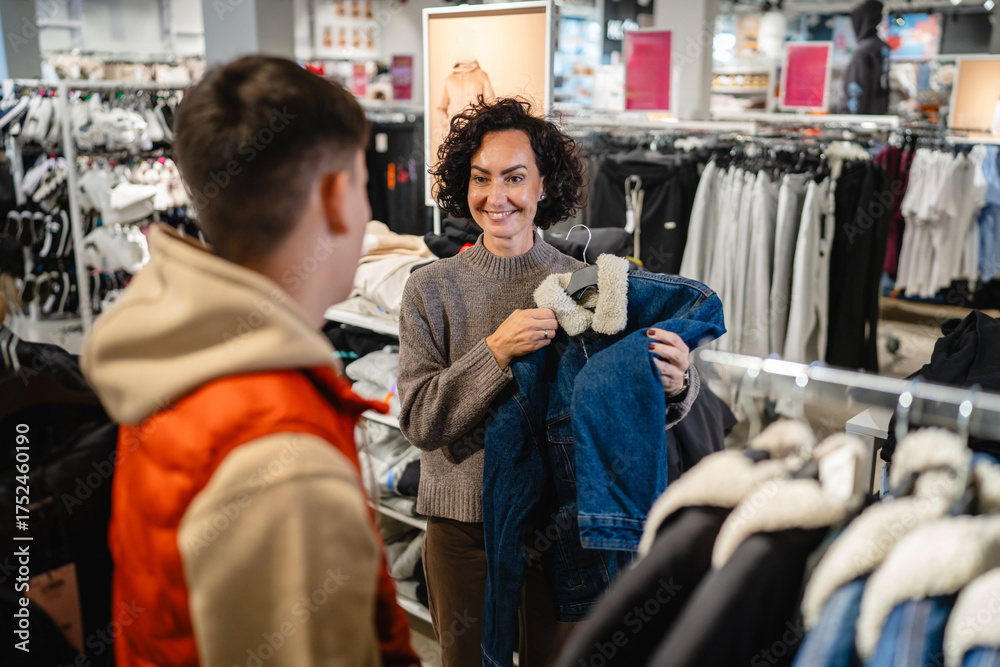 Fototapeta premium Woman smiling showing denim jacket to young son
