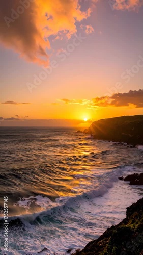 Golden sunset reflecting off ocean waves crashing against rocky coastline, creating a dynamic and vibrant coastal scene at dusk, perfect for travel videos