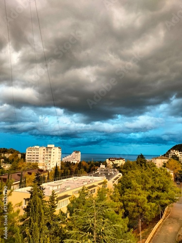 Wallpaper Mural rustic landscape. the sea, the buildings, the trees. large clouds in the sky. bright natural colors Torontodigital.ca