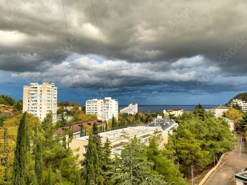 Wallpaper Mural rustic landscape. the sea, the buildings, the trees. large clouds in the sky. bright natural colors Torontodigital.ca