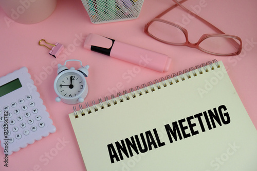 Annual Meeting text on a white notebook on pink background