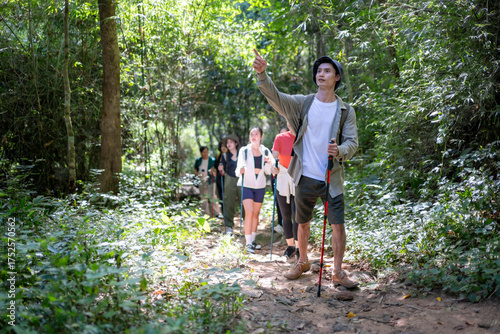Obraz na plátně Young man guiding hiking group through forest trail