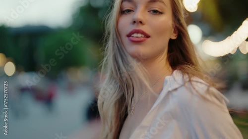 A carefree woman with a joyful expression enjoying herself in an urban park setting. Her hair is tousled by the wind, reflecting happiness and freedom. Young Beautiful Woman Enjoying The Outdoors
