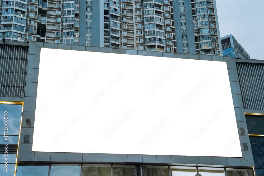 Obraz premium A mockup of a blank white billboard framed by a modern building facade, ideal for advertising