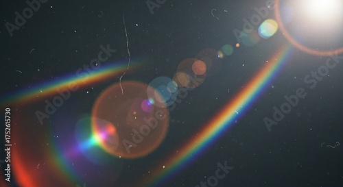 Lens flares and rainbow effect against dark, grainy background with dust/scratches