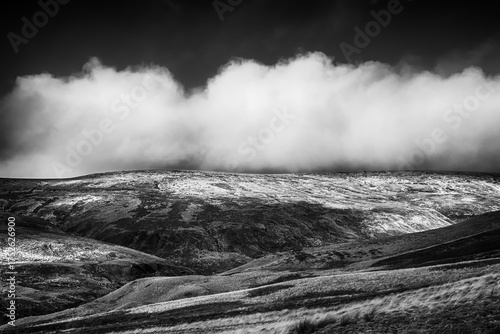 Fotografie Low cloud rolling over remote upland hills in black and white