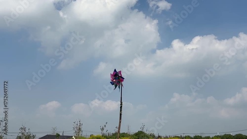 青空の下で回るカラフルな風車と穏やかな風景
