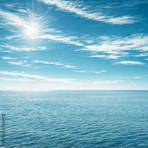 Bright sun shining over calm blue ocean waters and sky