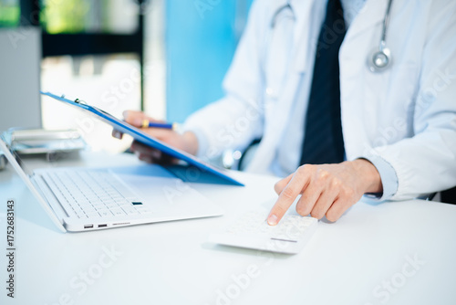 Healthcare costs and fees concept.Hand of smart doctor used a calculator and smartphone, tablet for medical costs at hospital