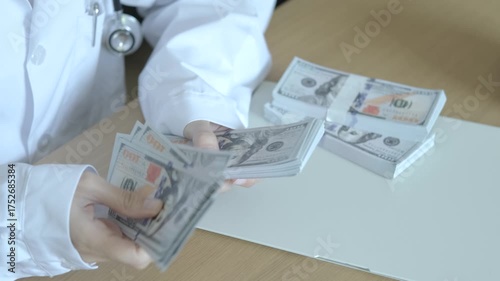 Doctor counting stacks of dollar bills on desk, concept of medical expenses, healthcare finance, and income from hospital business or insurance claim.