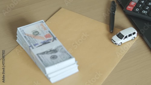 Car key, toy vehicle, and dollar bills on table, concept of car loan, vehicle financing, and business agreement for automobile purchase or sale.