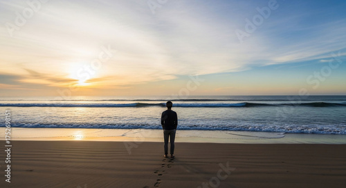 Solitary figure contemplates ocean sunrise horizon