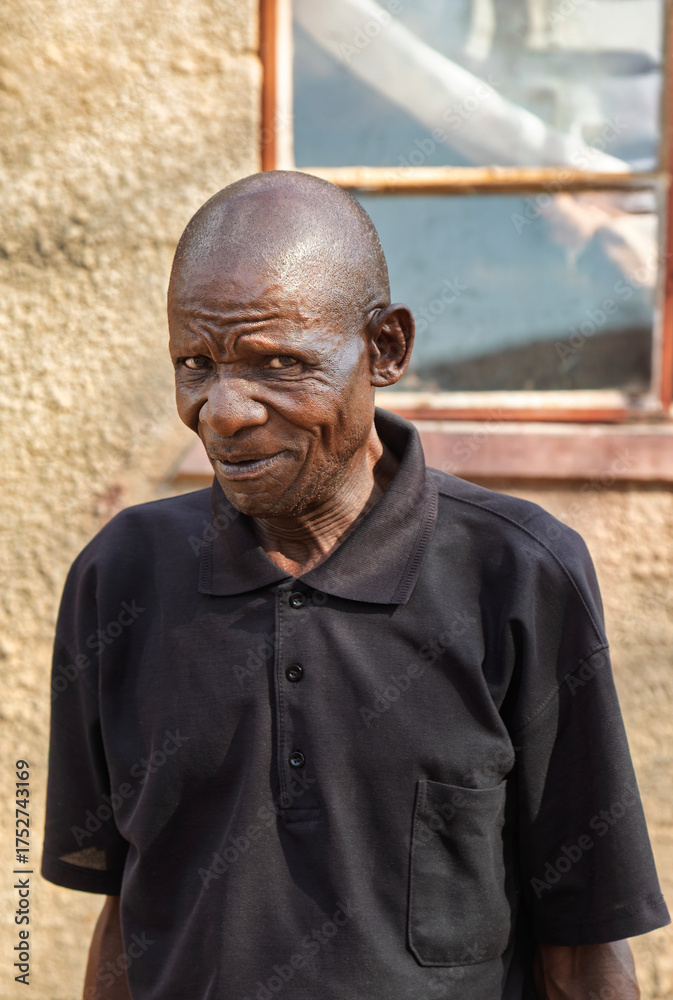 Naklejka premium single african old man portrait, in the village, standing in front of the house, rural life in Botswana,