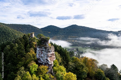 Morgennebel über der Burgruine Fleckenstein in den Vogesen. Drohnenaufnahme der Burgruine Fleckenstein im Elsass, umgeben von dichtem Wald und mystischem Morgennebel. 