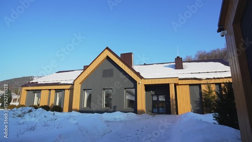 Long wooden cabin lies peacefully amid snow and tender pines. Minimalist design merges cozy mountain living with elegant tradition