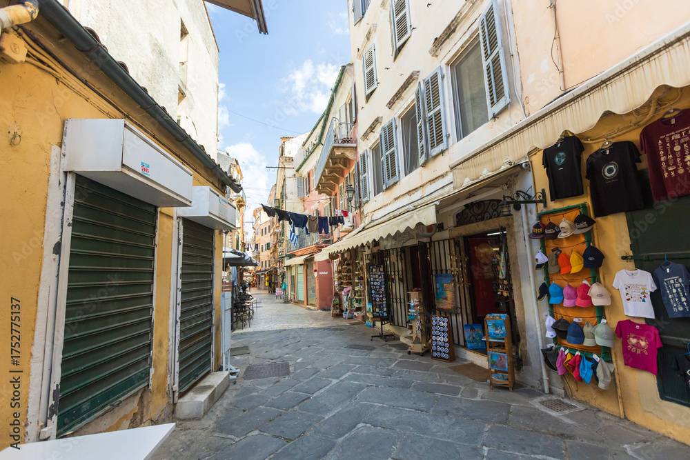 Fototapeta premium Colorful Corfu Town street with pastel facades, hanging laundry, and souvenir shops.