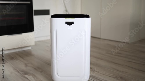 Modern air dehumidifier operating on wooden floor in bright minimalist kitchen white appliance with digital indicator showing humidity level symbolizing clean air and home comfort technology