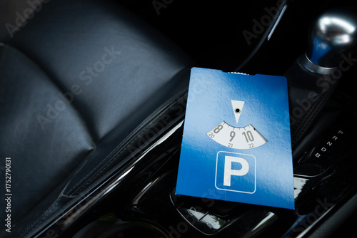 Close up blue parking disc in the car. Parking time restrictions in busy parking lots. Limited time duration park place zone.