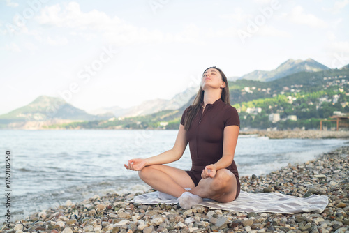 Young woman practicing yoga on seashore outdoor fitness and active lifestyle enjoying fresh air