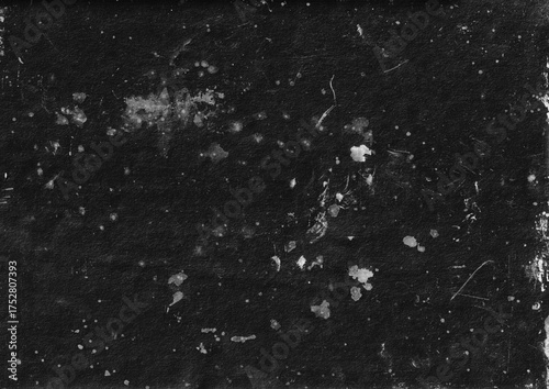 Dark grunge paper texture with white stains and scattered dust specks. Rough surface, worn and aged paint smudge for overlay design.