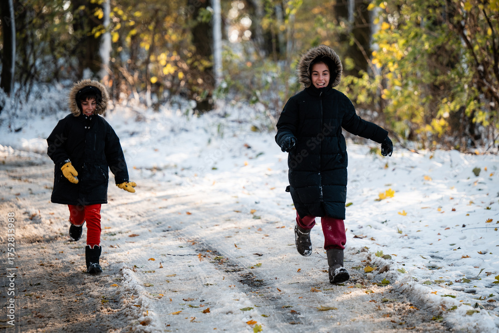 Fototapeta premium Children running in snow on forest path