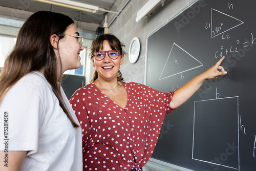 Foto Smiling teacher explaining geometry on blackboard to student