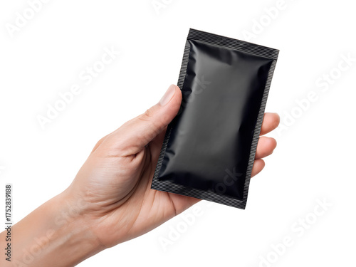 A hand holds a simple black sachet, a blank sealed rectangular pouch package, ready for branding, transparent png isolated.