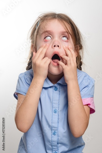 Young girl with surprised expression, eyes wide open, mouth agape, hands covering face. A candid shot of childlike wonder.