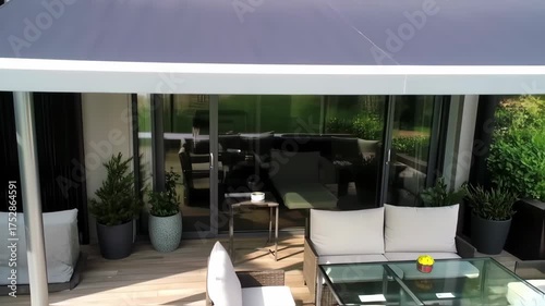 Gray retractable awning over a modern balcony with potted plants and patio furniture