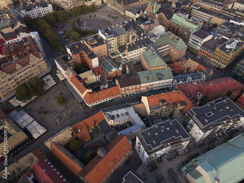 Aerial view of the vibrant Lilla Torg square, where historic buildings with terracotta roofs meet modern architecture under a soft, fading sunlight, Malmo, Sweden.