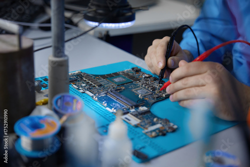 Closeup of an electronics repair skilled technician engaged in detailed motherboard work for repairs