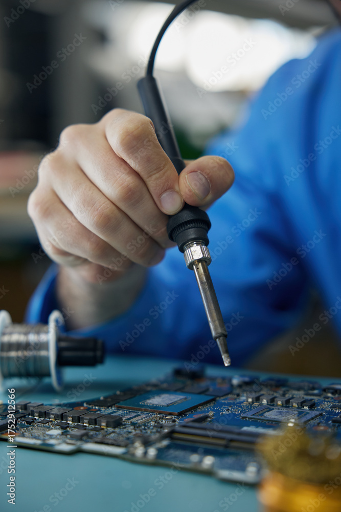 Fototapeta premium Closeup of an individual skillfully using a soldering iron on a motherboard