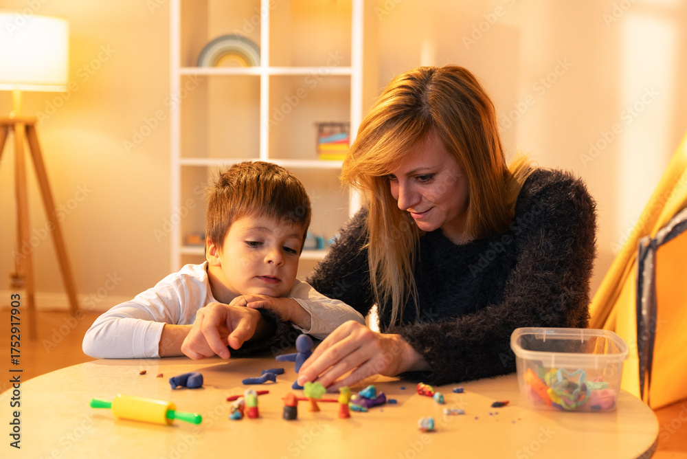 Fototapeta premium Childminder and boy playing with modeling clay at home