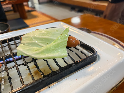 ウインナーにキャベツを被せて焼いてる。焼肉屋の風景。