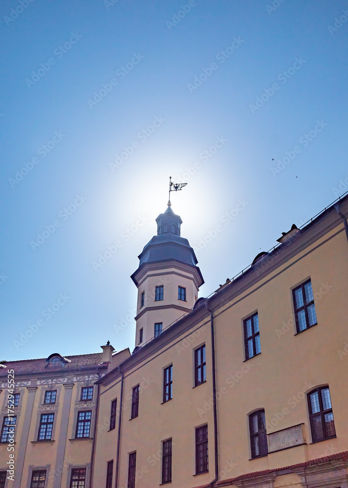 Fototapeta premium low-angle shot of Nesvizh Castle, Belarus. The tower with windvane is against bright sun and blue sky.