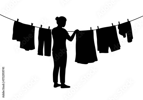 Silhouette of a woman hanging clothes on a clothesline to dry outside.