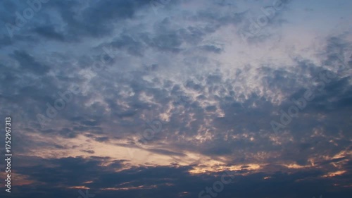 Cloudy sky at sunset. Light pink light from the setting sun. Romantic background with clouds.