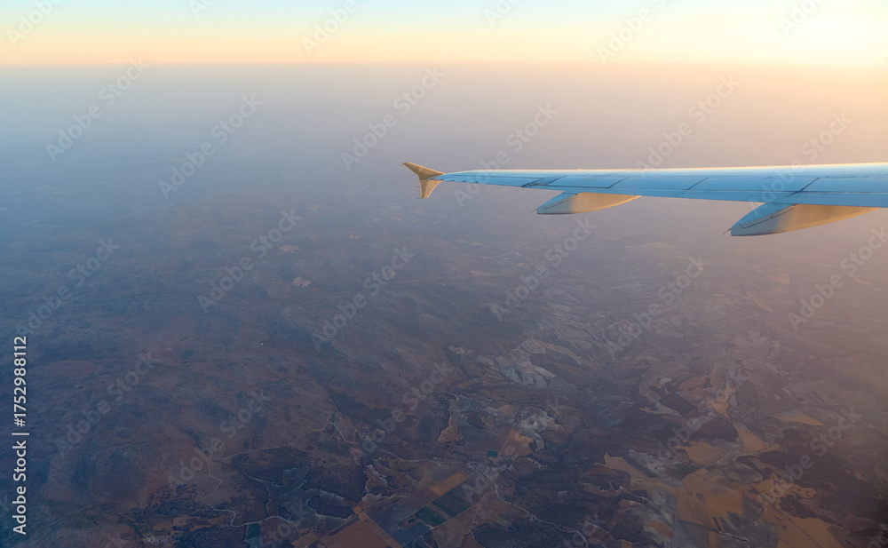 Naklejka premium Scenic view from an airplane wing during sunset over rolling hills and valleys