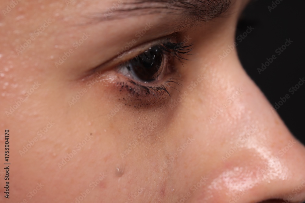 Fototapeta premium Sad woman crying on black background, closeup