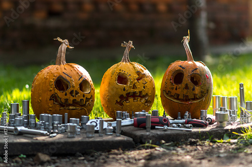 autumn holiday Halloween 2025 scary pumpkins orange mechanics with a set of tools for car repair in blood red light in the dark