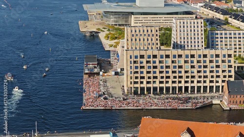 Aerial drone view of the busy Islands Brygge waterfront filled with swimmers, sunbathers, and cyclists in Copenhagen, Denmark